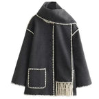 Women's oversized coat in soft fabric featuring an integrated scarf and fringe detailing for added texture and warmth.