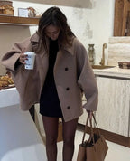 Women's oversized coat featuring wide lapels, button closure, and a cozy fabric, perfect for layering in cool weather.