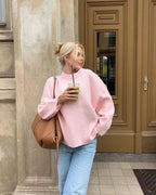 Women's oversized soft pink sweater made of cozy knit fabric, featuring long sleeves and a relaxed fit for comfort.