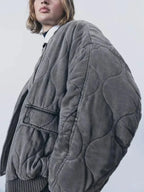 Women's quilted bomber jacket with snap closures, featuring soft polyester fabric and a stylish, layered design.