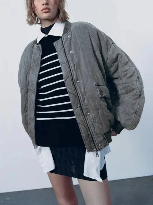 Women's quilted bomber jacket featuring snap closures, made from durable fabric with a stylish, lightweight design.