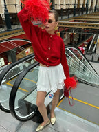Women's red cardigan featuring feather sleeves, button front, and soft knit fabric for a stylish and comfortable fit.