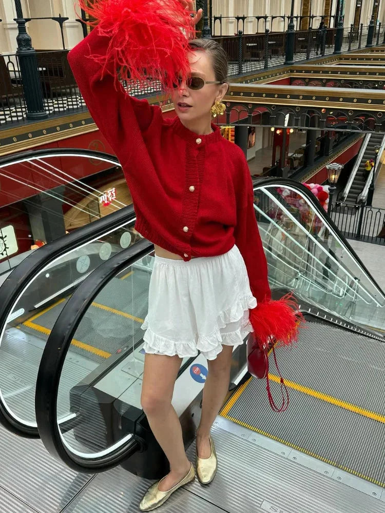 Women's red cardigan featuring feather sleeves, button front, and soft knit fabric for a stylish and comfortable fit.
