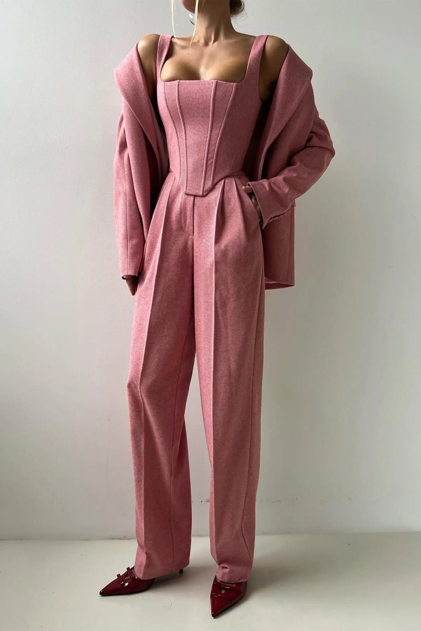 Women's tailored three-piece set in soft fabric, featuring a fitted top and matching trousers with a structured blazer.