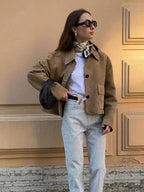 Women's tan cropped jacket featuring front pockets and a lightweight fabric, perfect for layering in cooler weather.