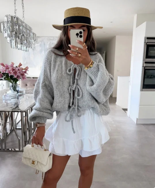 Women's knitted cardigan featuring a tie-front design and oversized sleeves, perfect for layering in cooler weather.